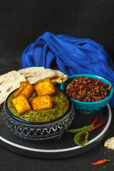 Palak paneer, a traditional dish of Indian cuisine. The two main ingredients are spinach and homemade fresh cheese. Close-up on a black background,vertically with space