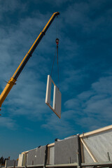 Building a prefabricated wooden house - raising or hoisting house section with a help of a crane.