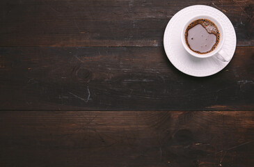 white ceramic cup with black coffee on brown wooden table