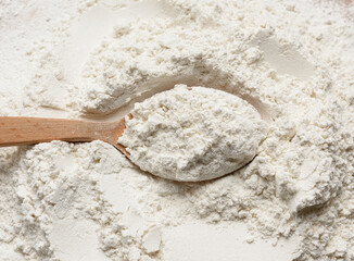 white wheat flour in a wooden spoon, top view