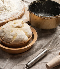 kneaded dough made of white wheat flour in a wooden plate and a metal kneading bucket
