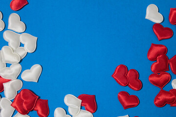 Small red and white hearts that are scattered on a blue background.