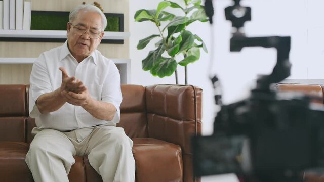 Family concept of 4k Resolution. An elderly Asian man is giving an interview about his health in the living room.