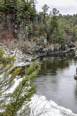 Rocky cliffs along the winter snow and icy river