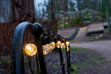 The rail of the bridge is decorated with a garland of light bulbs with a blurred background.
