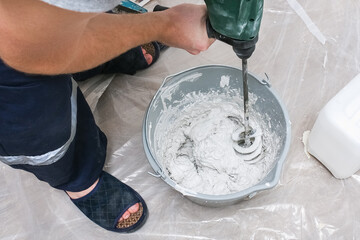 A male worker spreads the putty mixture and flattens the wall.