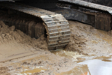 excavator tracks in the water. repair and expansion of a road in the north of gatchina, russia. reportage shooting.