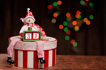 486.	A snowman figure is sitting on a decoupage box and holding a smaller box with two cubes...