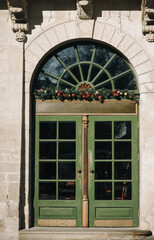 Fototapeta na wymiar The doorway of the old Baroque style with a complex design with green wooden door. Christmas tree decoration on New Year's Eve. The facade of the building in Lviv, Ukraine.