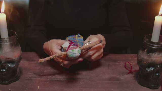 Close up of woman fortune teller sticks a needle into voodoo doll in terrible magic ritual