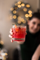 Pretty young woman holding up a delicious cranberry cocktail at Christmas.