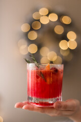 A womans hand holding a Christmas cranberry cocktail.