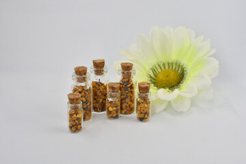 Close up view of small glass jars filled with pollen from organic flowers, isolated on a white background.