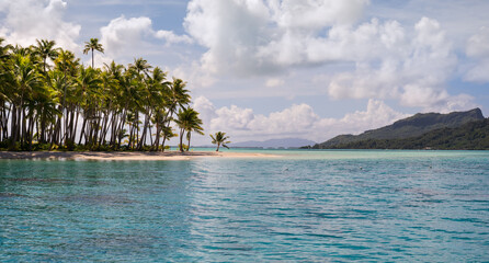 Polynesian island, the turquoise sea and the white clouds in the blue sky create a peaceful scene