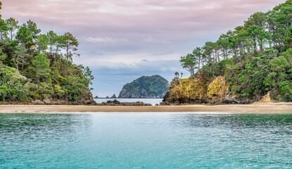 Bay of Islands New Zealand. A picturesque scene with reflections on the water from the land and colorful sky frame a distant island