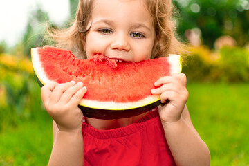 Adorable baby eating red watermelon in backyard garden. Funny kid outside enjoying summer days and fresh fruits. Cute toddler girl having picnic in park. International Children&rsquo;s Day concept.