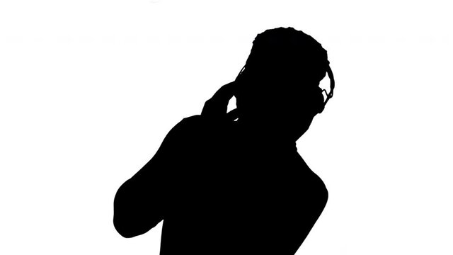 Silhouette Happy African american holding headphones with his hands and dancing to the music beat while smiling at camera.