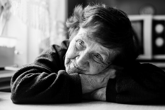 Close-up portrait of an old woman in her home. Black and white photo.