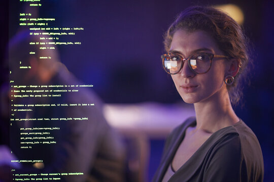 Portrait of professional young soft developer wearing eyeglasses working in evening looking at camera, medium close-up portrait