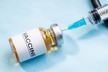 vaccine injecting concept. vaccination bottle with syringe near stethoscope over blue surgery background. above view. illustrative