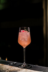 A gourmet mixed drink cocktail of sweet pink lemonade vodka and gin martini, garnished in the bar with bottles in the dark background