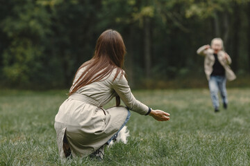 Fashionable mother with daughter. People walks outside. Woman in a brown coat.