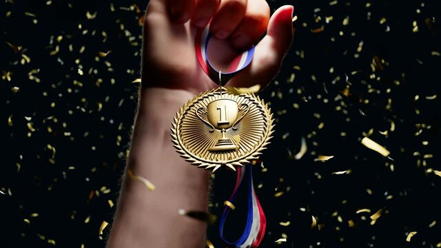 Rising hand holding a shiny gold medal. Top winner with first prize. Victory.