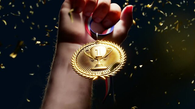 Rising hand holding a shiny gold medal. Top winner with first prize. Victory.