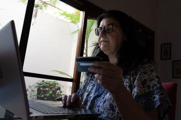 Mujer sosteniendo tarjeta de crédito usando computadora portátil , compras en linea,  ventas con...