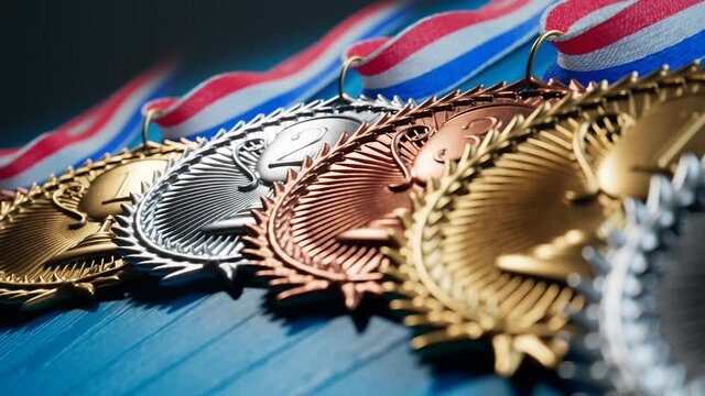 Gold Silver and Bronze Sports Medals with Ribbons on Blue Wood