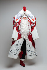 Stock photo of full length Father Frost in traditional costume with long white beard standing in tree yoga pose with arms in namaste above his head.
