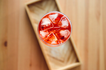 orange spritz cocktail in tall glass on wooden table with golden light shinining from nearby window,