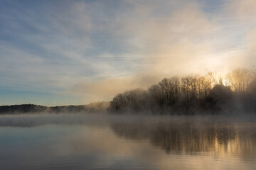 Fototapeta na wymiar The sun rises over the foggy waters of Lake Lanier during winter in Georgia; silence; peace