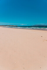 pristine wild landscape at Clifton Beach in Tasmania, Australia with wavy blue ocean and golden sand next to a rugged coastline
