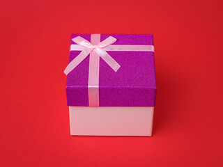 Stylish gift box with a bow on a red background.
