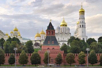 Fototapeta na wymiar The walls of the Moscow Kremlin with the Kremlin embankment. Medieval Russian architecture, white-stone cathedrals with Golden domes, Ivan the Great bell tower. UNESCO monument