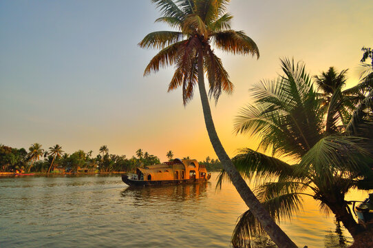 A boat sailing on Kerala backwaters during sunset.