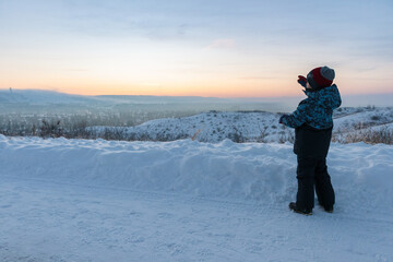 Fototapeta na wymiar Young boy looking at snowy landscape at sunset