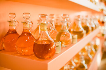 Fragrances in the glass bottles on the shelves. Liquid oils and perfumes in big bottles. Crafts supplies.