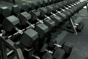 A rack of heavy hex dumbbells at a gym or fitness club. Workout and pyramid training or running the...