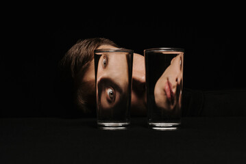 strange portrait of a man looking through two glasses of water
