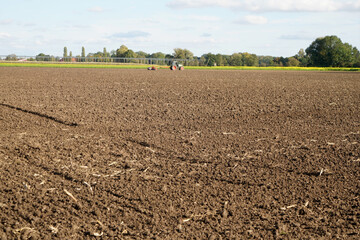 A closeup of cultivated farmland with a tractor working