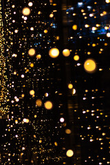 Fototapeta na wymiar Perfect bokeh for a festive New Year and Christmas background. Defocused abstract circles of yellow and blue light on windows, vertical frame