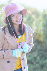 Asian woman wearing a pink hat is posing with happiness on a green background.