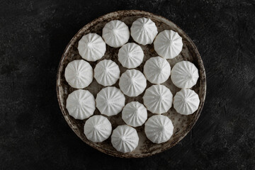 White sweet meringue in ceramic round bowl and plate on concrete background. Top view.