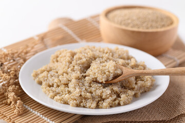 Cooked brown quinoa seeds on white dish with spoon for eating, Healthy vegan food