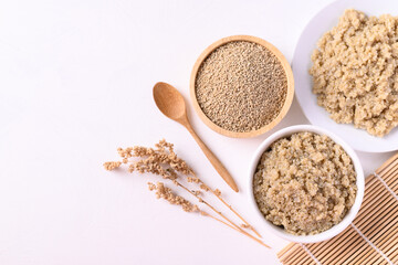 Cooked brown quinoa seeds and raw quinoa seeds in a bowl on white background, Top view, Healthy vegan food