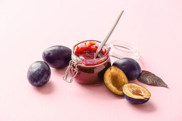 Glass jar with delicious homemade plum jam on color background