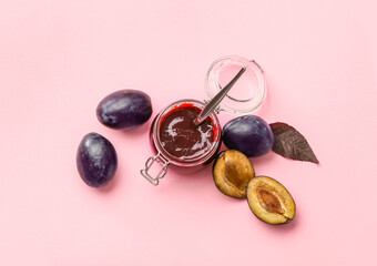 Glass jar with delicious homemade plum jam on color background