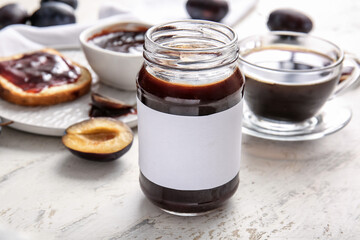 Glass jar with delicious homemade plum jam on table
